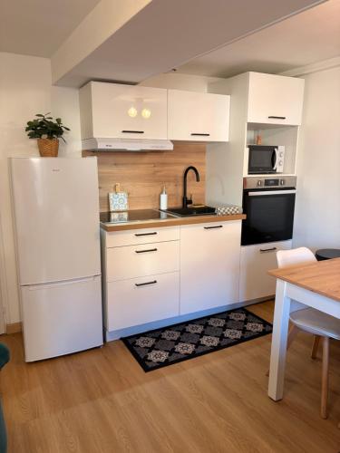 a kitchen with white cabinets and a white refrigerator at L'atelier du Charme Dole Centre in Dole