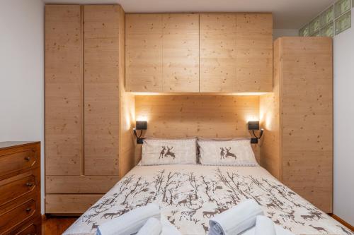 a bedroom with a large bed with a wooden headboard at La Casetta Vintage - Base Milan Cortina 2026 in Bormio