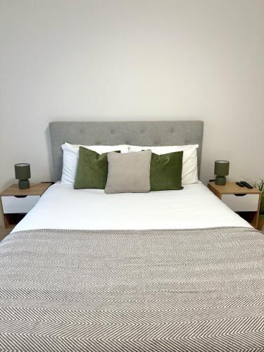 a bedroom with a large white bed with green pillows at 22nd Floor Luxury City Centre Apartment in Belfast