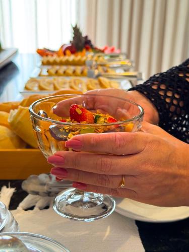 una donna che tiene una ciotola di vetro davanti a un tavolo di Hotel Icaraí Beach a Icaraí