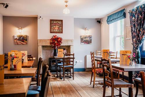 um restaurante com mesas e cadeiras e uma lareira em The Railway em Skipton