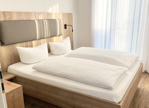 a bed with white sheets and pillows in a room at WeberHof Appartements in Burg
