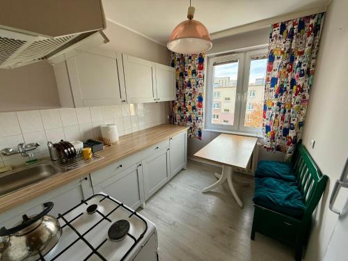 波兹南Pokoje na Wichrowym的厨房配有白色橱柜、桌子和炉灶。
