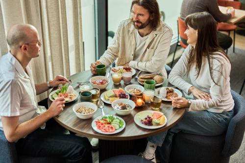 トロムソにあるスマートホテル トロムソのテーブルの周りに座って食事をとる人々のグループ