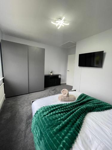 a bedroom with a bed with a green blanket on it at Luxury Airport Home with Driveway and Garden- Sleeps 7 in Ashley