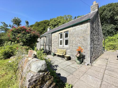 ein Steingebäude mit einer Bank davor in der Unterkunft Dunmore Cottage in Whitehouse