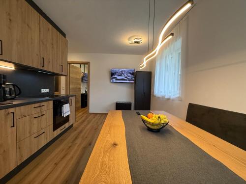 Una cocina con un bol de fruta sobre una mesa de madera. en Haus Schernthaner, en Saalbach Hinterglemm