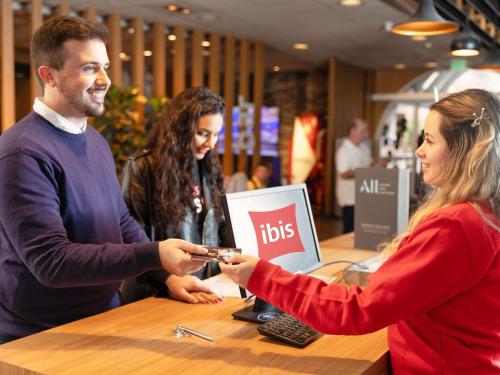 un homme et une femme debout à un comptoir jouant à un jeu dans l'établissement ibis Sao Paulo Paulista, à São Paulo
