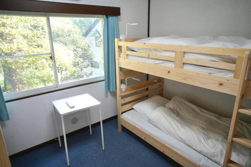 Un dormitorio con dos literas y una ventana. en Dear Hostel Hakuba, en Hakuba