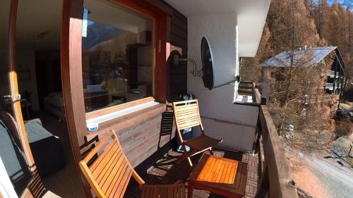 a balcony with two chairs and a window at Erables 454 in Zinal