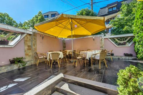 eine Terrasse mit gelbem Sonnenschirm, Tischen und Stühlen in der Unterkunft Hotel Darling in Bankja