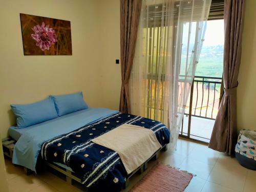 Un dormitorio con una cama y una ventana con balcón. en Lukas' Place, en Kampala