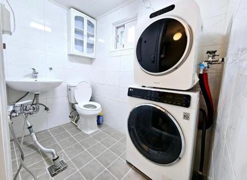a washer and dryer in a bathroom with a sink at 숲애스테이 in Hagwanggyo-dong
