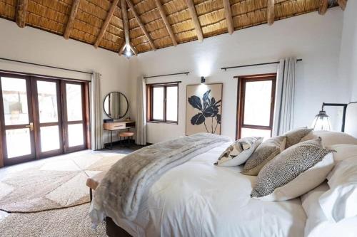 a bedroom with a large white bed and windows at Landrift Villa in Phalaborwa