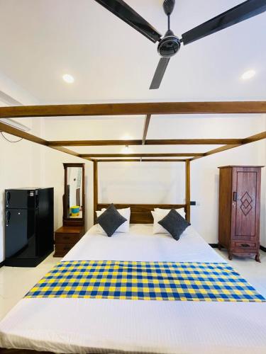 a bedroom with a large bed with a ceiling fan at Sanu Surfing Villa in Weligama