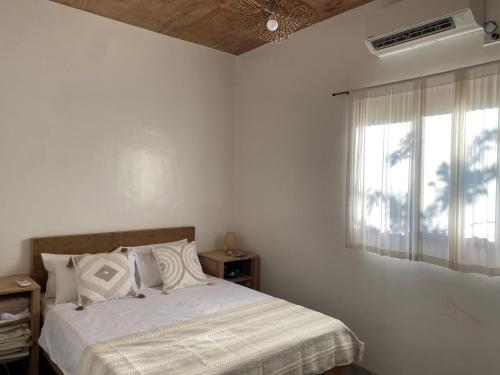 a white bedroom with a bed and a window at Malinka House in Alegria
