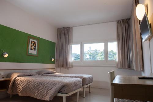 a bedroom with a bed and a desk and a window at Hotel Giardino in Breno