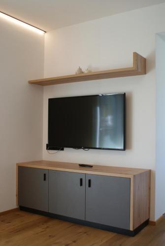 un téléviseur à écran plat accroché au mur dans l'établissement Alpenglow Apartments, à Collalbo