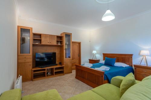 a bedroom with a bed and a tv and a couch at Casa dos Amigos in Pico da Pedra