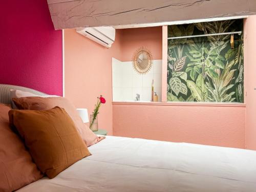 a bedroom with pink walls and a bed with a window at Le Mexico Duplex Agréable in Lespignan