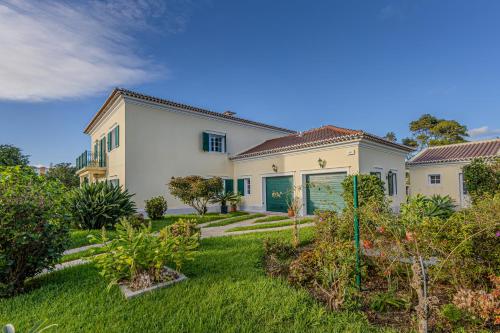 a large white house with a yard with plants at Casa dos Amigos in Pico da Pedra