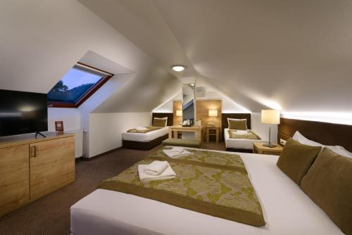 a bedroom with a large bed and a tv in a room at Hotel Honti Wellness és Konferencia Szálloda in Visegrád