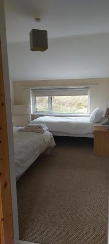 a bedroom with two beds and a large window at Crillaun Cottage in Foxford