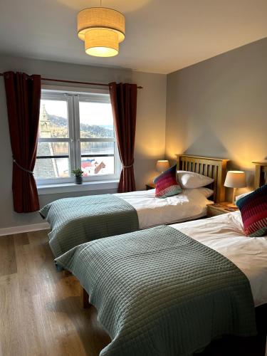 two beds in a room with a window at Apartment in Highlands of Scotland - Fort William in Fort William