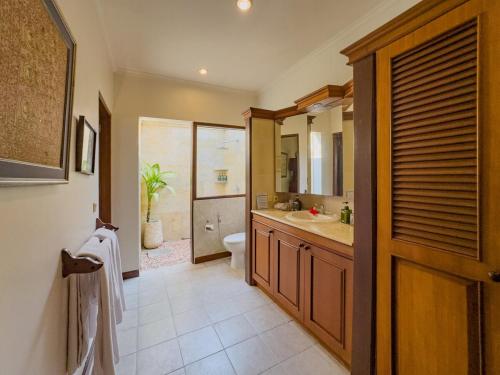 a bathroom with a toilet and a sink and a mirror at Arjuna Villa 3 Bedroom Villa Seminyak in Seminyak