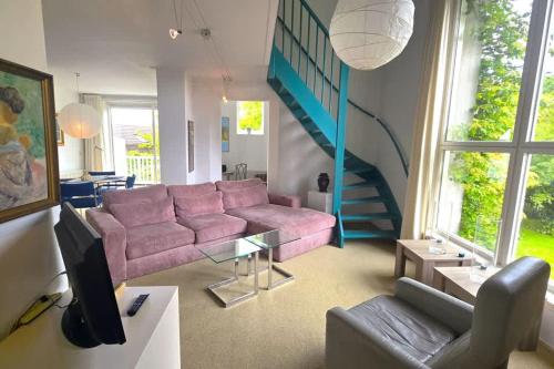 - un salon avec un canapé rose et un escalier dans l'établissement Hello Zeeland - Noordstraat 13-01, à Domburg