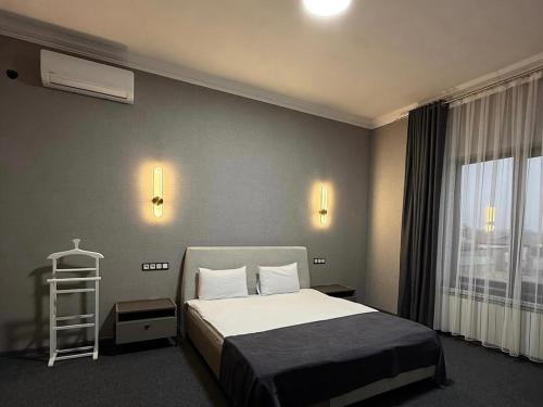a hotel room with a bed and a window at Hotel Marjan in Shymkent