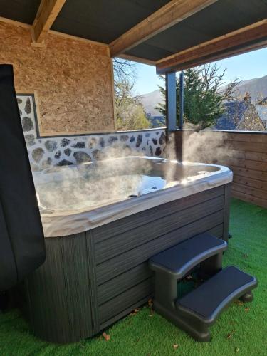 a jacuzzi tub in a backyard with a chair at Les Roses Des Bois in Murat-le-Quaire