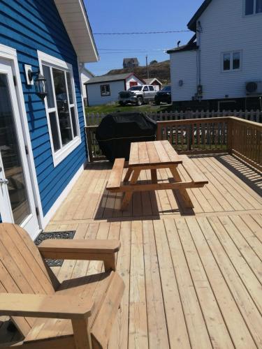 eine Holzterrasse mit einem Picknicktisch und einem Stuhl in der Unterkunft Oceanview Cottage in Twillingate