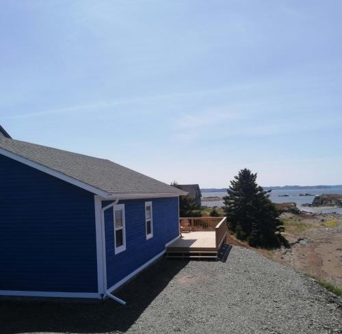ein blaues Haus mit einer Veranda und einer Terrasse in der Unterkunft Oceanview Cottage in Twillingate