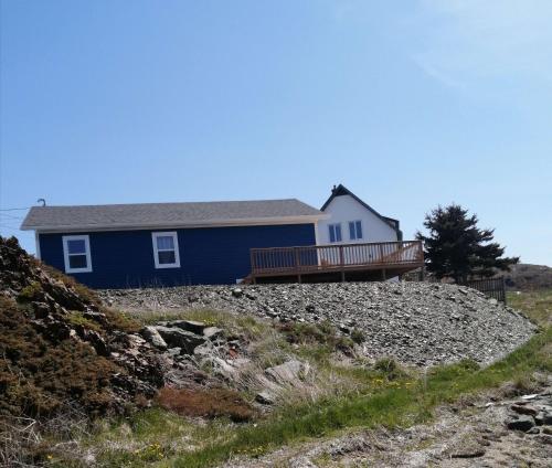 une maison bleue au sommet d'une colline rocheuse dans l'établissement Oceanview Cottage, à North Twillingate Island