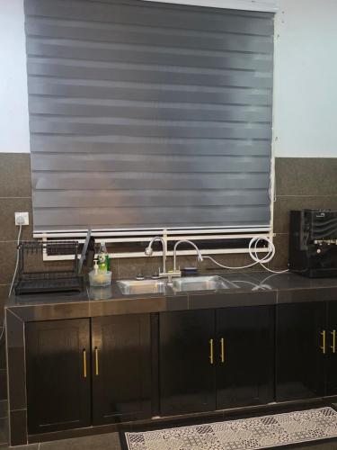une cuisine avec un évier et un store au-dessus d'une fenêtre dans l'établissement D'Stay Anak Dara Kijal, à Kijal