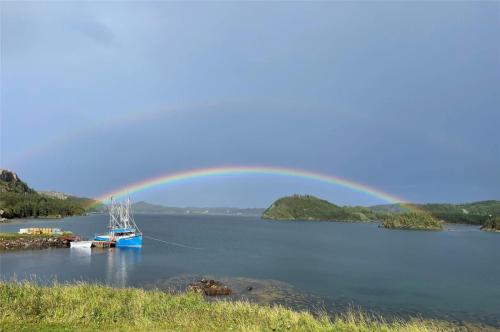 a rainbow over a body of water with a boat at Seaside Serendipity Cottage in Herring Neck