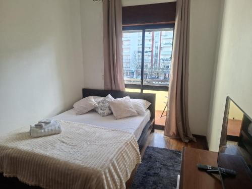 a bedroom with a bed and a large window at Quarto duplo em casa compartilhada in Santarém