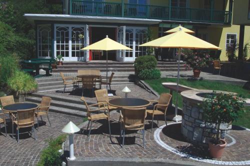 an outdoor patio with tables and chairs and umbrellas at Die WUNDER s Ferienpension in Pörtschach am Wörthersee
