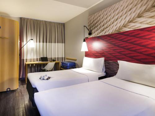 a hotel room with two beds and a desk at ibis Navegantes Itajai in Itajaí