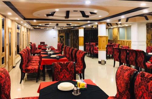 ein Restaurant mit roten Stühlen und Tischen, auf denen Teller standen in der Unterkunft Daryal hotel in Kārandūkai