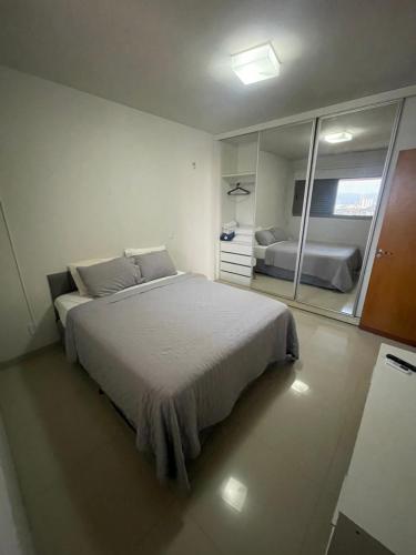 ein Schlafzimmer mit einem großen Bett und einem Spiegel in der Unterkunft Ap 2 quartos em frente ao Campim Dourado Shopping in Palmas