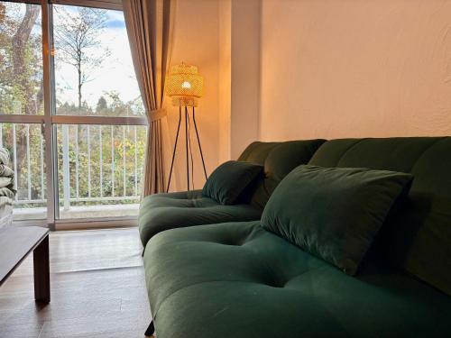 a living room with a green couch and a window at FUJI Forest House203 in Gotemba
