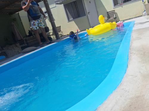 Ein Kind spielt in einem Pool mit einem Spielzeug im Wasser in der Unterkunft Pousada Recanto Turmalina C Piscina in Pontal do Paraná
