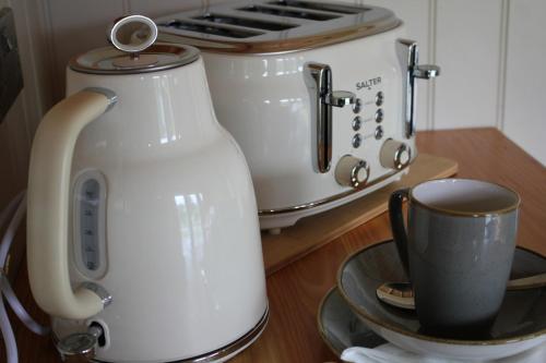 a tea kettle and a toaster and a cup on a table at Quiet Skye Winter hideaway Moluag in Portree