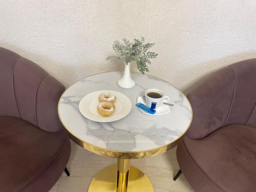 einen Tisch mit einem Teller Donuts und einer Tasse Kaffee in der Unterkunft Green Hotel in Almaty