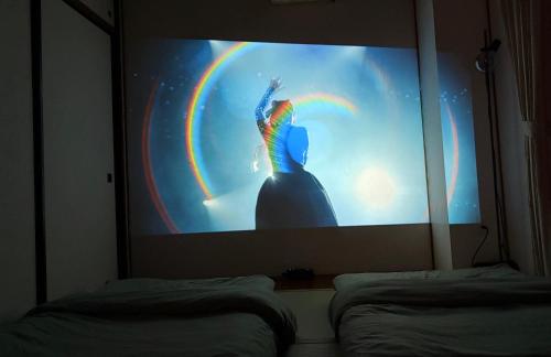 a projection screen with a person on it with a rainbow at FUJI Forest House203 in Gotemba