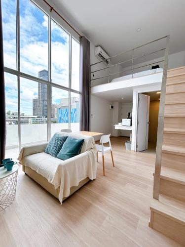 a bedroom with a bed and a table and large windows at Komfort Duplex BTS Ratchayothin in Bangkok