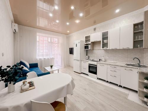 a kitchen with white cabinets and a table in a room at 2х комнатная квартира в ЖК Ирина in Pavlodar