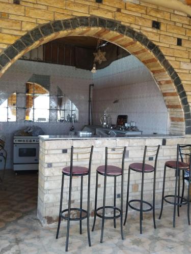 Una cocina con una encimera con cuatro taburetes. en Ramsess Hotel, en Luxor